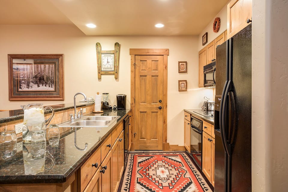Your rustic-modern kitchen welcomes you with warm wood cabinets, granite counters, and charming mountain decor—perfect for preparing memorable meals together.