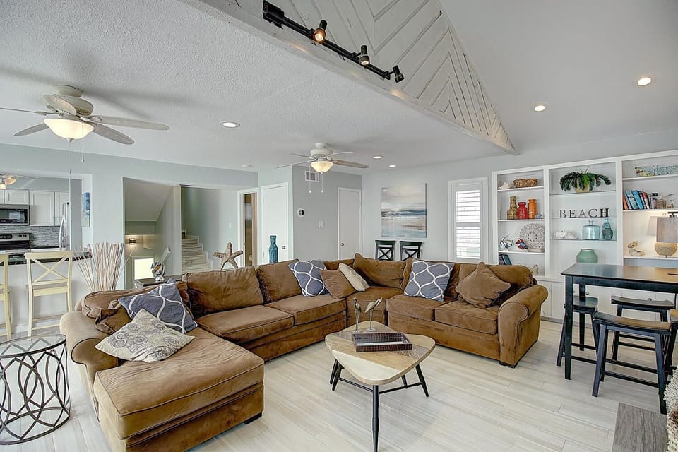 Unwind in your spacious living area featuring plush sectional seating, coastal decor, and an open-concept design perfect for gathering with loved ones.