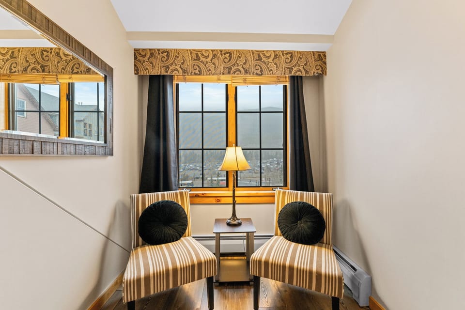 Settle into your cozy window nook with striped chairs and city views, perfect for morning coffee or evening relaxation.