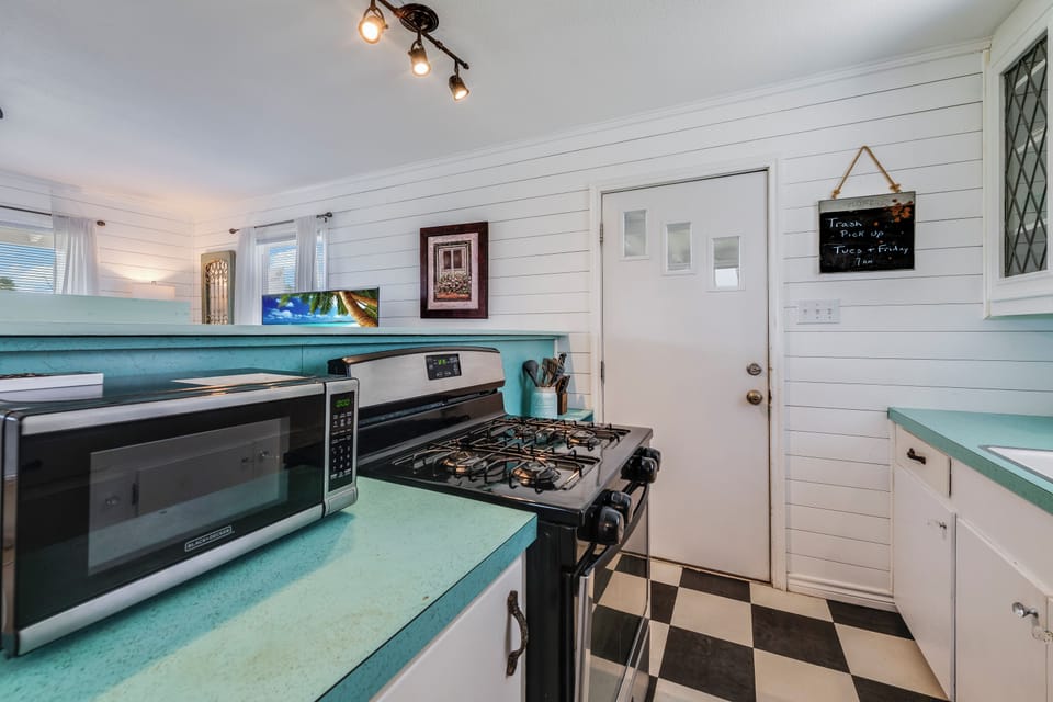 Step into your fully equipped kitchen featuring charming turquoise countertops, modern appliances, and classic checkerboard flooring. Whip up your favorite meals with ease in this bright, welcoming space.