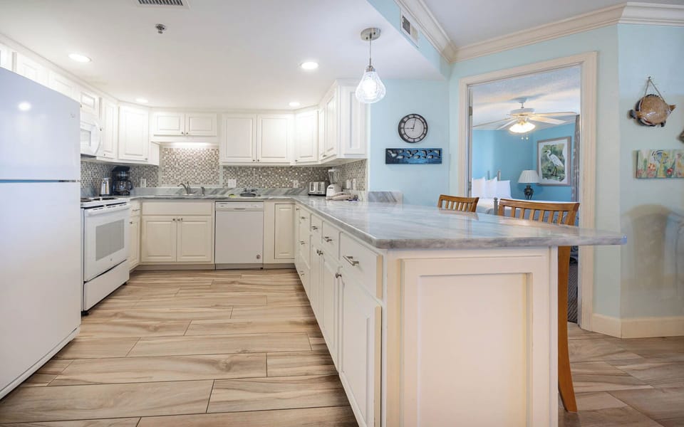 The kitchen features white cabinetry, a marbled countertop, stylish backsplash, and a breakfast bar with seating
