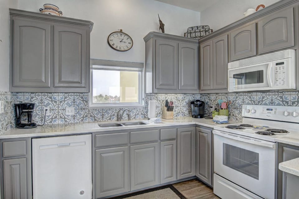 Your fully-equipped kitchen awaits with elegant gray cabinetry, modern appliances, and charming tile backsplash for cooking memorable meals.