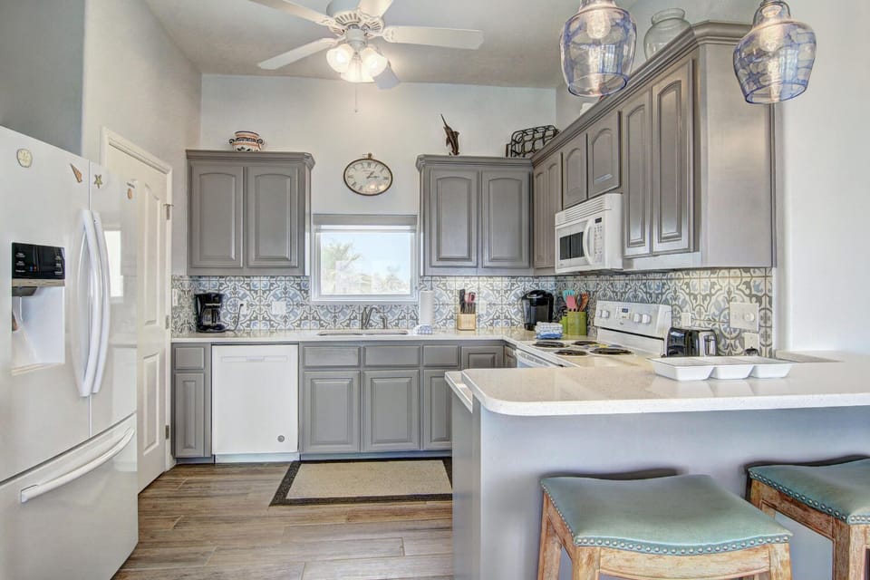 Cook meals with ease in your fully equipped kitchen, featuring elegant gray cabinets, modern appliances, and charming coastal touches.