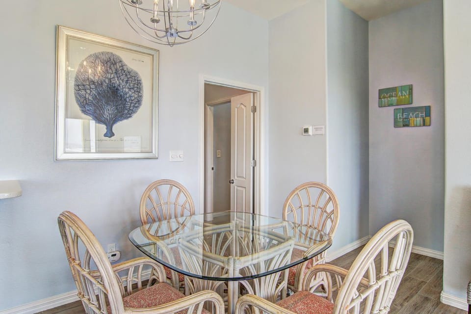 Gather around your elegant glass dining table beneath coastal artwork, where every meal becomes a special occasion in this stylishly appointed space.