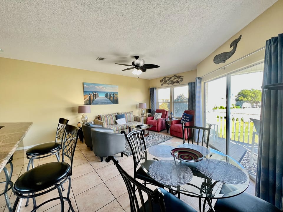 Your bright, coastal-themed living space opens to peaceful balcony views, where comfortable seating and dining await your Florida getaway.