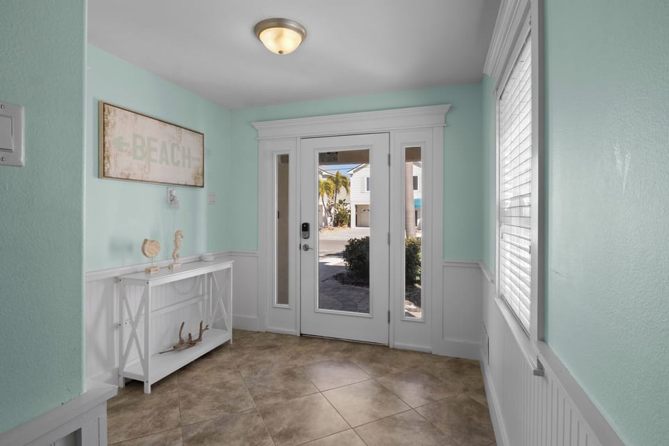 Your coastal entrance greets you with soothing mint walls and beach-themed charm, setting the perfect tone for your vacation retreat.