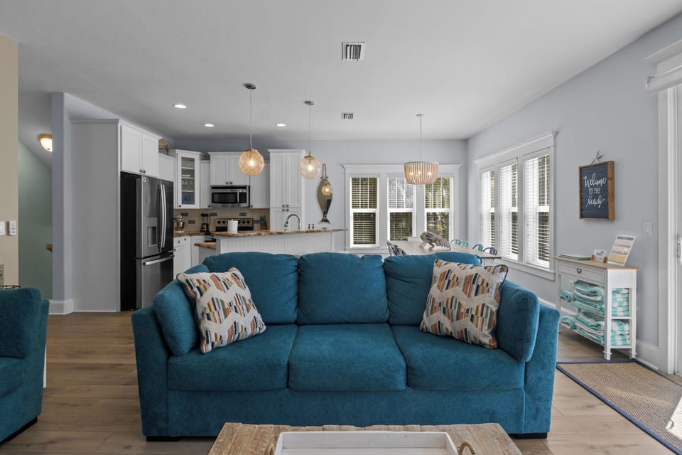 Unwind on the plush blue sofa in your bright, open-concept living space where modern comfort meets coastal charm.