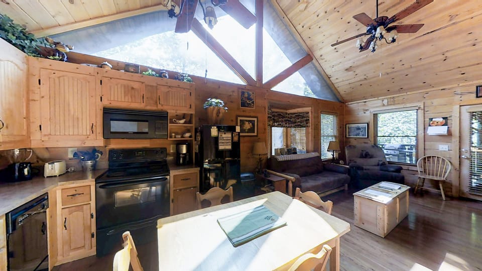 Open kitchen and dining area with all appliances and seating for four at Always Kiss Me Goodnight cabin in Pigeon Forge, Tennessee — just 10 minutes from downtown Pigeon Forge.