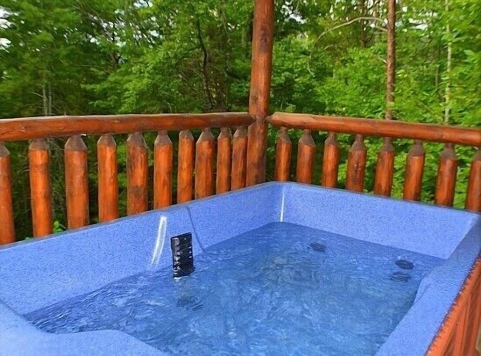 Relaxing private hot tub on the deck surrounded by lush wooded scenery at Always Kiss Me Goodnight cabin in Pigeon Forge, Tennessee — just 10 minutes from downtown Pigeon Forge.