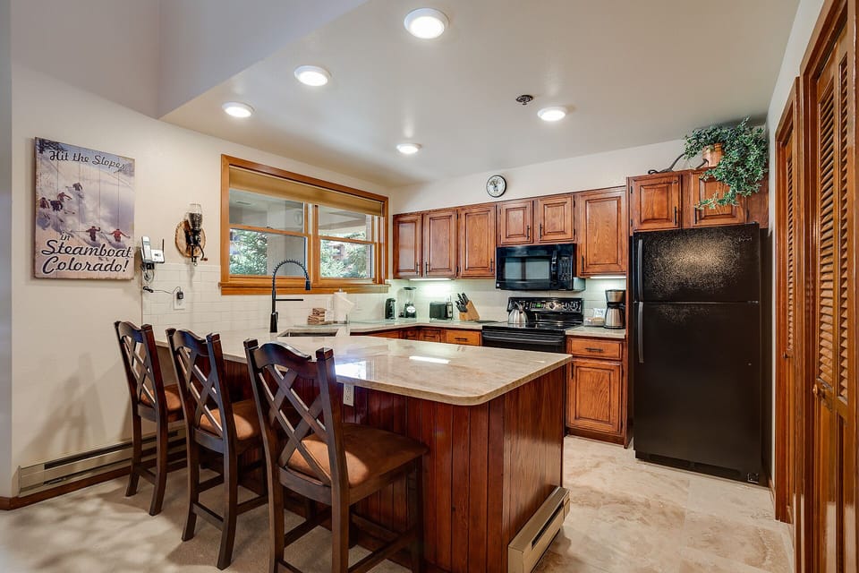 Your fully equipped kitchen features rich wood cabinets, granite countertops, and modern appliances, perfect for preparing family meals during your mountain getaway.