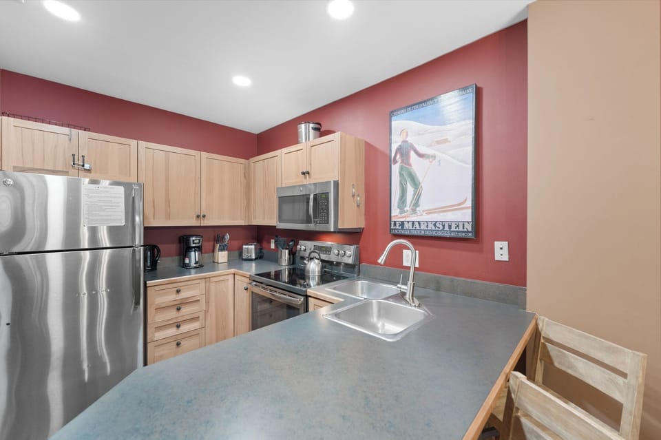 Your fully equipped kitchen features modern appliances and warm wood cabinets, perfect for preparing meals during your mountain getaway.