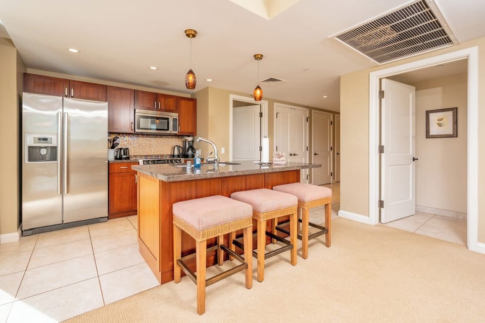 Warm island kitchen with bar seating, stainless appliances, inviting design.