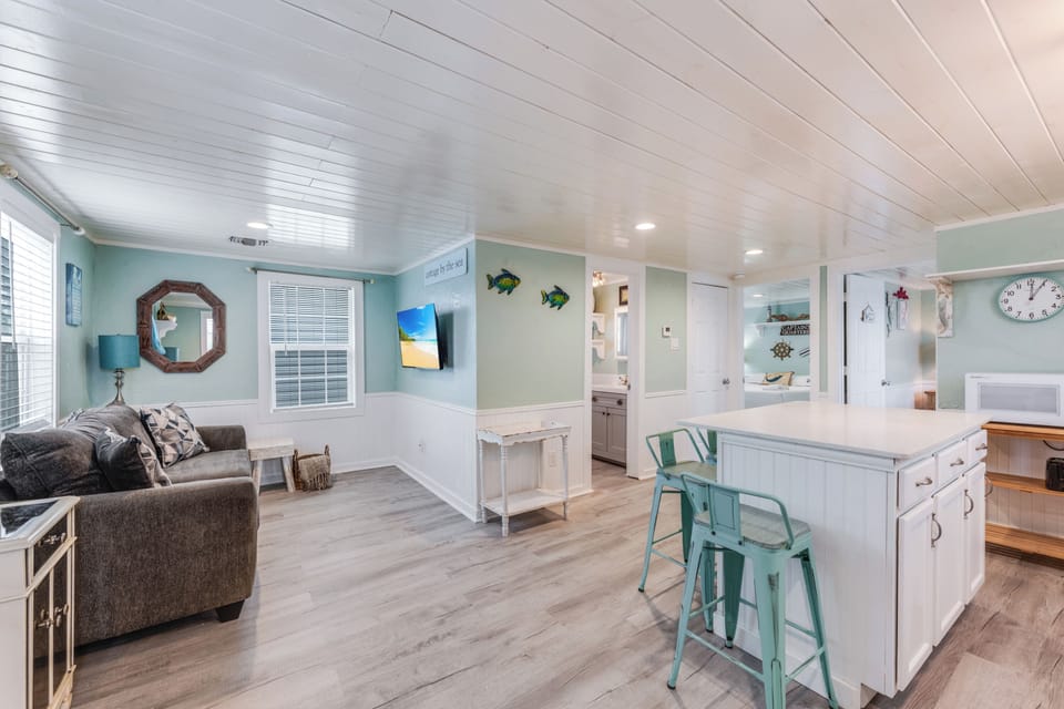 Relax in your coastal-themed open-plan space with aqua accents, comfy seating, and kitchen island—perfect for vacation living.