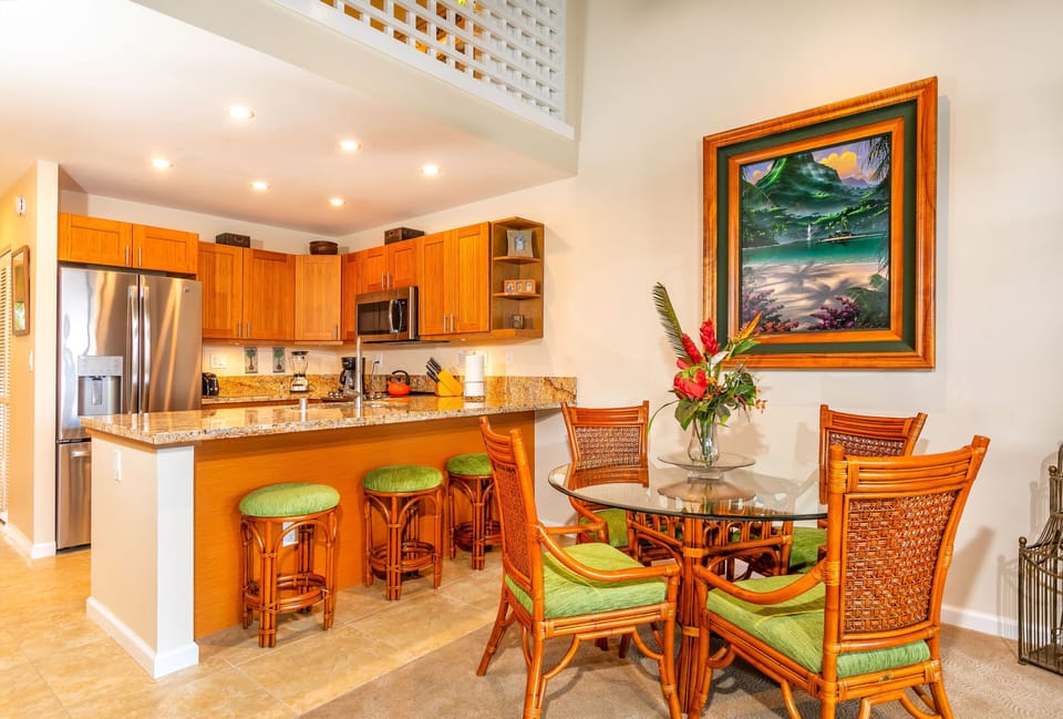 Step into your island retreat where warm wood tones, tropical art, and bright pops of green create a welcoming space. Gather at the breakfast bar or dining table, all within this open, light-filled living area.