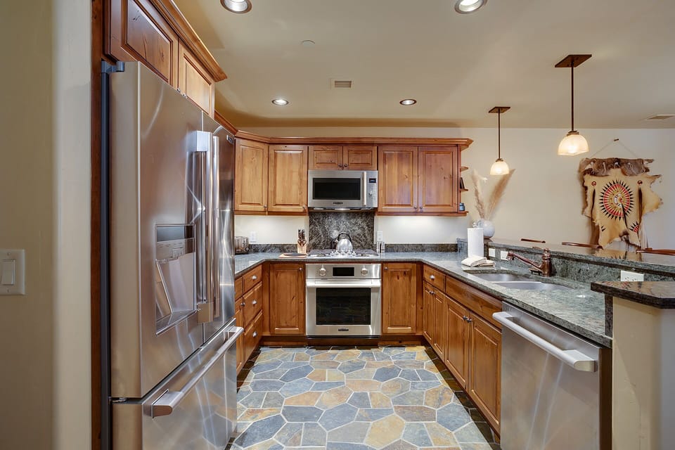 Step into your fully equipped gourmet kitchen with granite countertops, stainless steel appliances, and warm wood cabinetry perfect for creating memorable meals.