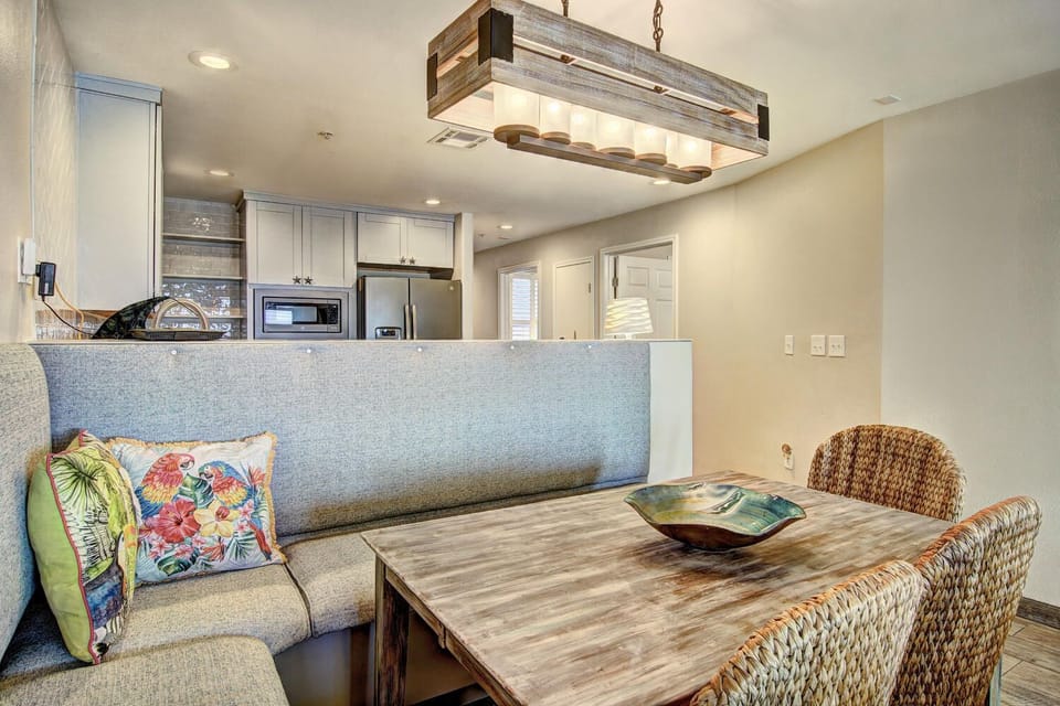 Your open-concept dining space flows seamlessly into the kitchen, featuring a rustic wood table under atmospheric lighting for memorable meals together.
