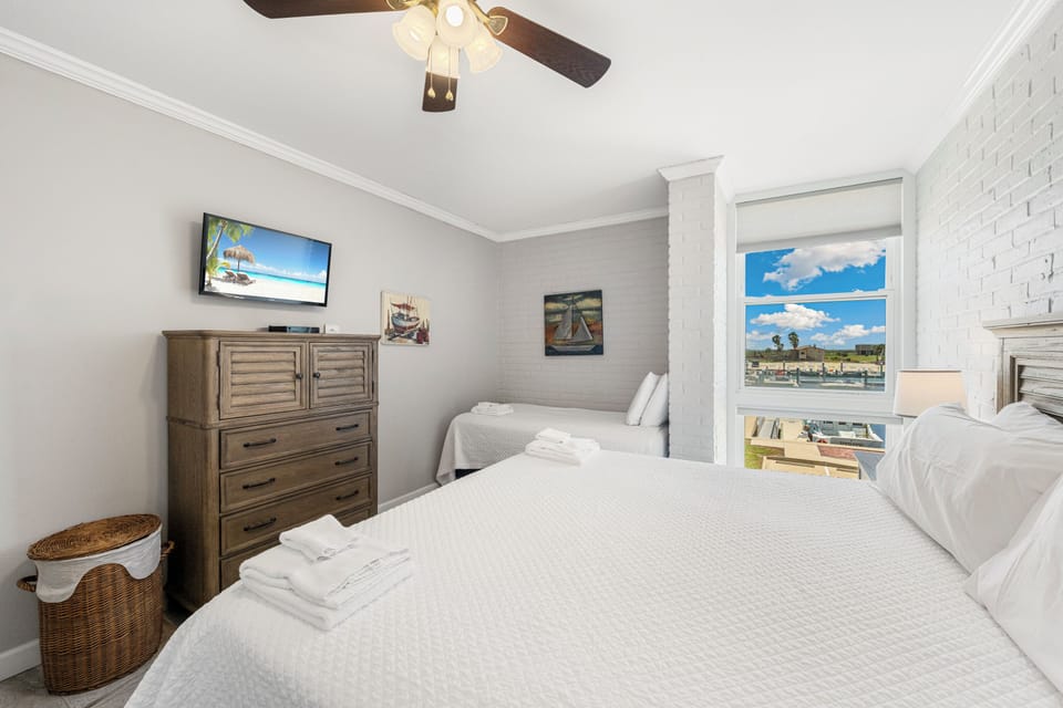 Unwind in your cozy bedroom with crisp white linens, waterfront views, and nautical touches that create the perfect coastal retreat.