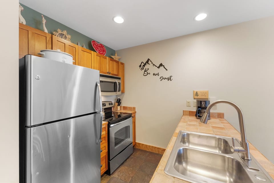 Your fully equipped kitchen awaits with stainless steel appliances, granite counters, and warm wood cabinets—perfect for preparing meals during your stay.