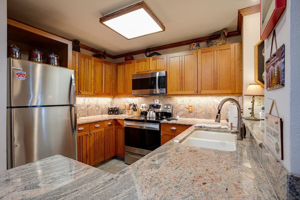 Your fully-equipped kitchen features granite countertops, stainless appliances, and warm wood cabinets for comfortable home cooking during your stay.