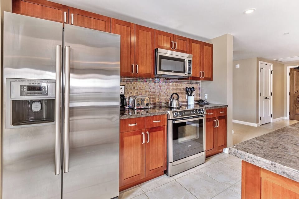 Modern full kitchen with stainless steel appliances and mosaic backsplash.