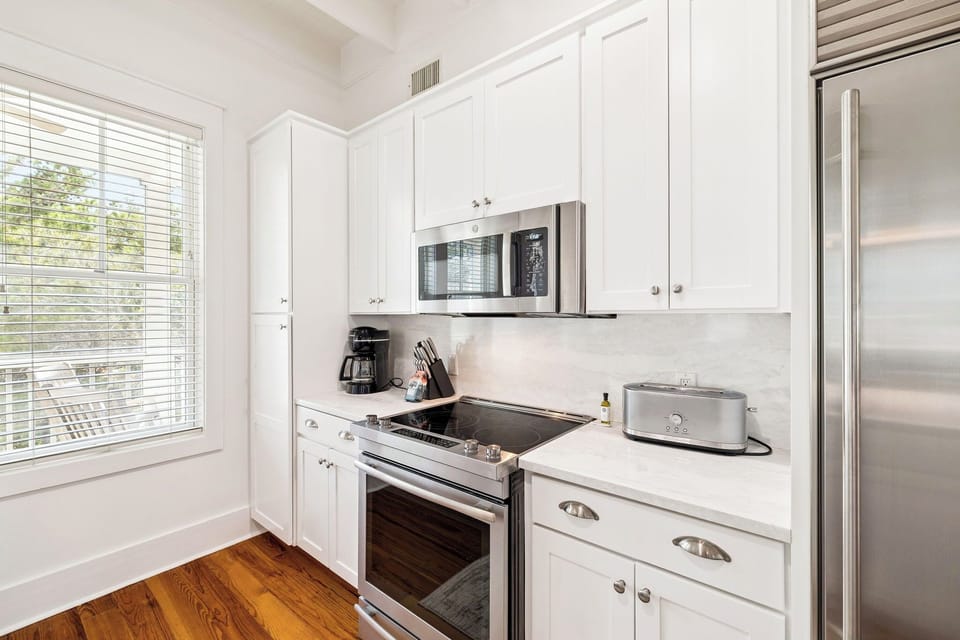 Your bright, fully-equipped kitchen awaits with gleaming white cabinets, stainless steel appliances, and marble countertops for memorable meal preparation.