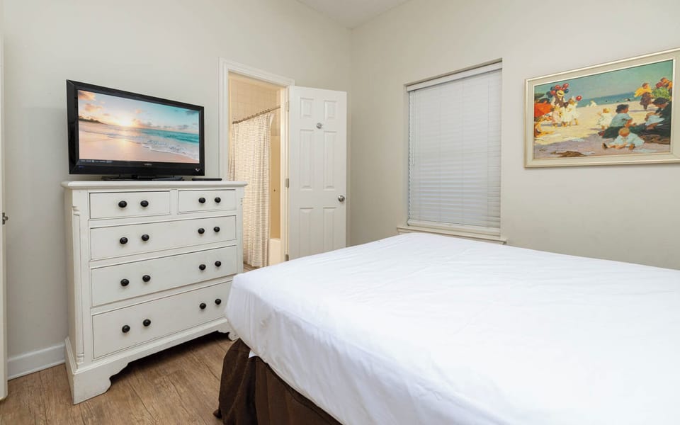 Inviting guest bedroom featuring a comfortable queen bed, a TV for entertainment, and natural light from the window