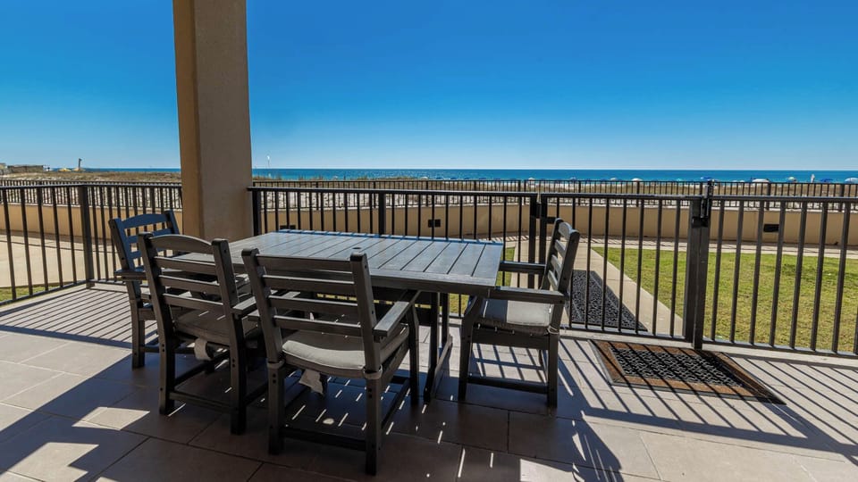 Enjoy meals or morning coffee at the outdoor dining table with a view of the sparkling beach in the distance