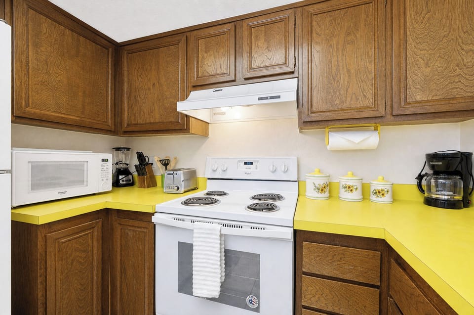 Step into your cheerful kitchen equipped with everything you need to prepare homemade meals, featuring bright yellow counters, a full-size stove, microwave, and coffee maker for your comfort.