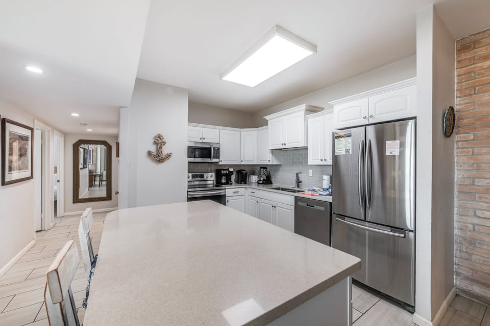 Your spacious kitchen awaits with pristine white cabinets, stainless steel appliances, and generous counter space for preparing memorable meals together.