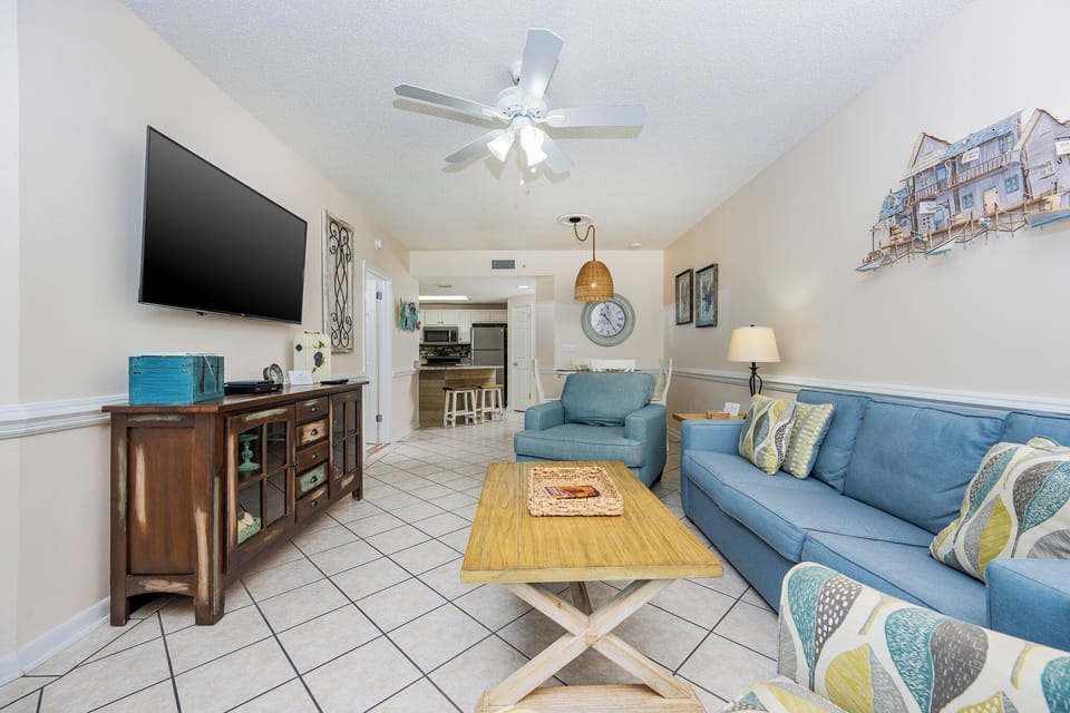 Relax in the inviting living area, featuring comfortable seating, a large TV, and coastal-inspired decor for your enjoyment