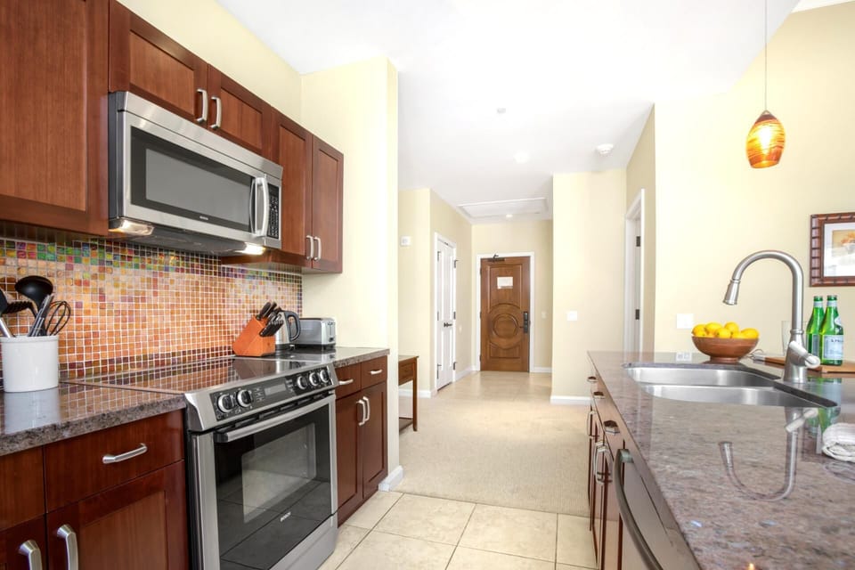 Modern kitchen with granite countertops, mosaic backsplash, and stainless appliances.