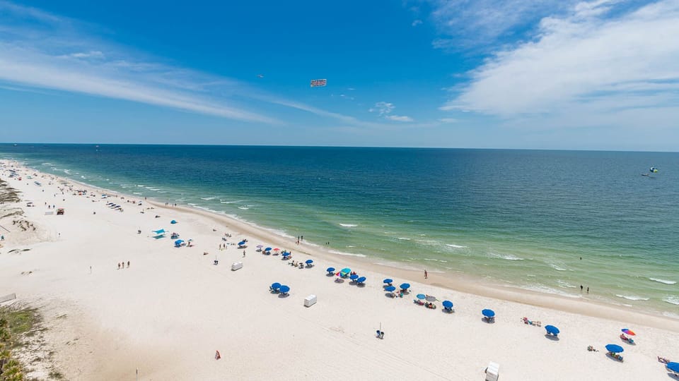 This breathtaking view showcases vibrant blue umbrellas on the sandy shore, perfect for a relaxing getaway
