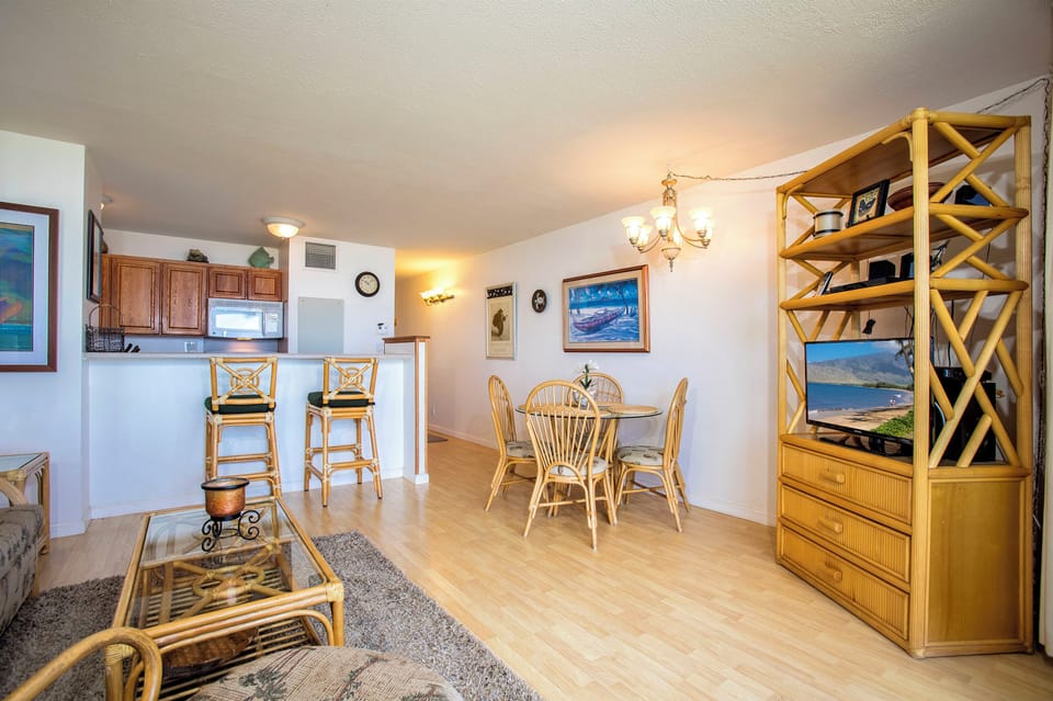 Bright, open living space with coastal charm, featuring bamboo furnishings, a cozy dining nook, and a fully-equipped kitchen where you can unwind after your seaside adventures.
