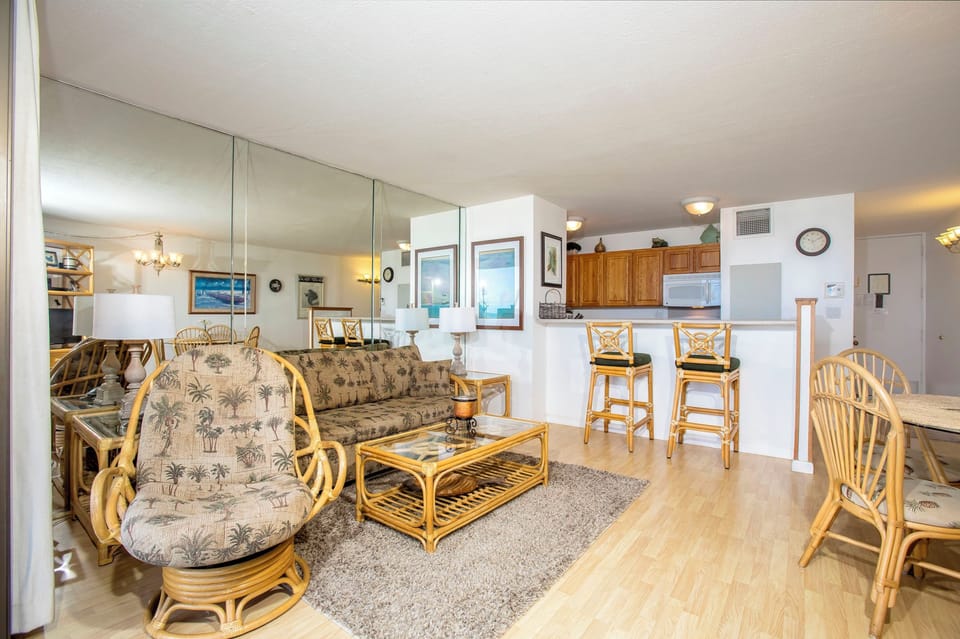 Step into this bright, open living area where coastal comfort meets convenience. Rattan furniture invites relaxation, while the fully-equipped kitchen and breakfast bar make meal prep a breeze.