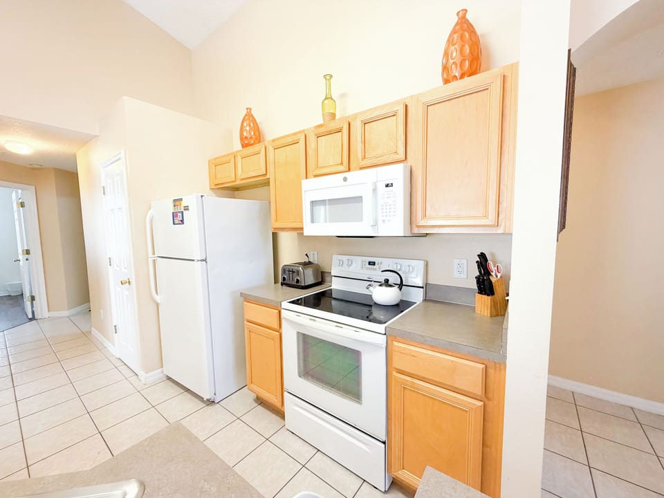 Fully equipped kitchen featuring a refrigerator, oven, microwave, ample cabinet space, and clean countertops for easy meal preparation.
