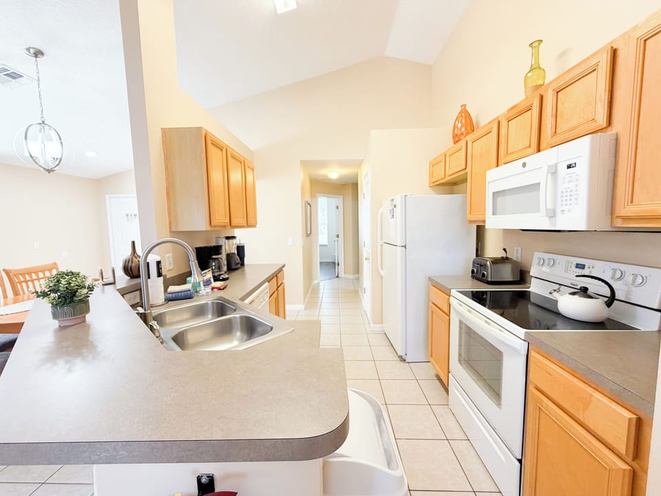 Fully equipped kitchen with ample counter space, modern appliances, and a convenient breakfast bar ideal for preparing meals at home.