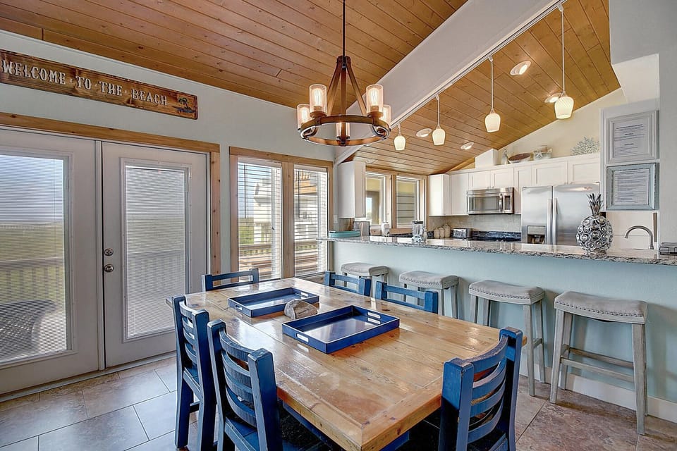 Gather around your spacious kitchen island or rustic dining table, where warm wood ceilings and coastal charm create the perfect setting for memorable meals together.
