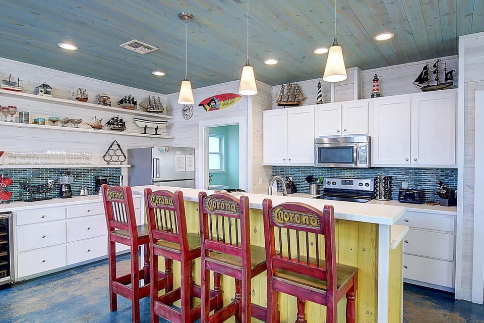 Your beach-themed kitchen invites culinary adventures with white cabinets, nautical decor, and a breakfast bar perfect for morning coffee.