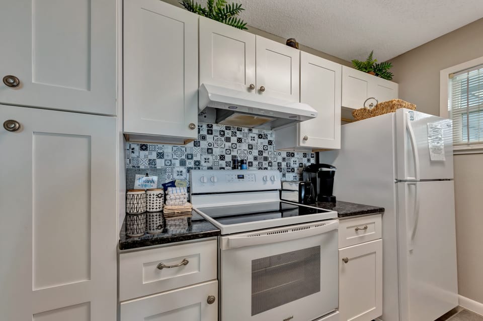 Your fully-equipped kitchen awaits with modern appliances and charming mosaic backsplash, perfect for preparing morning coffee or home-cooked meals.