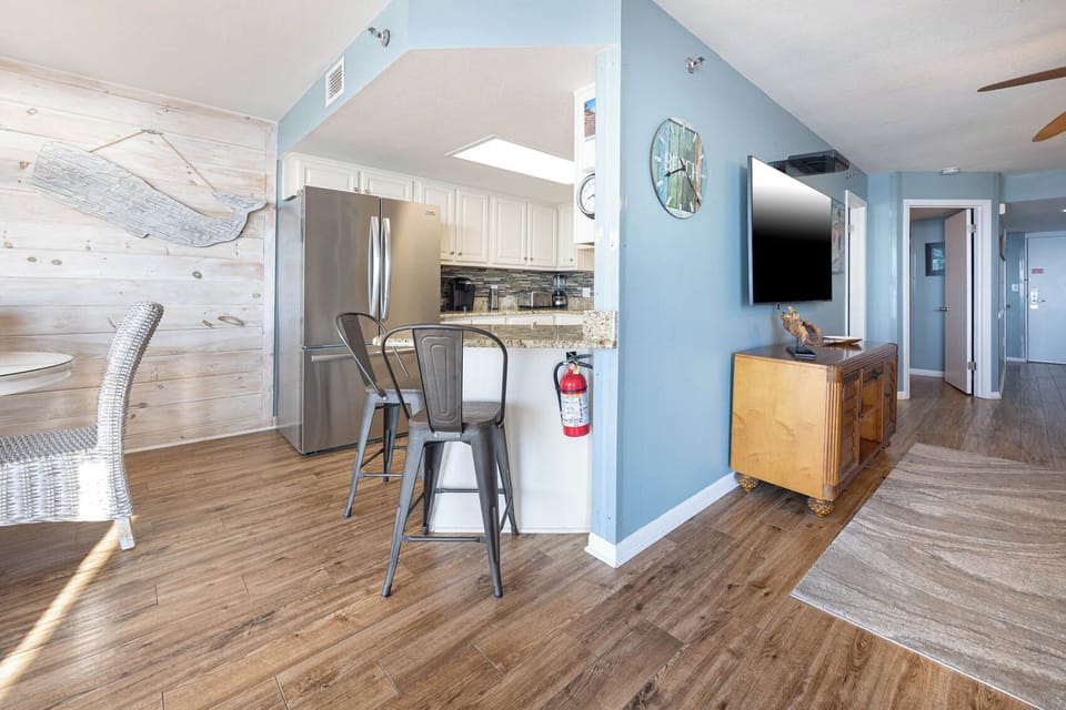 Kitchen area features a granite breakfast bar with seating, stainless steel appliances, and coastal decor accents