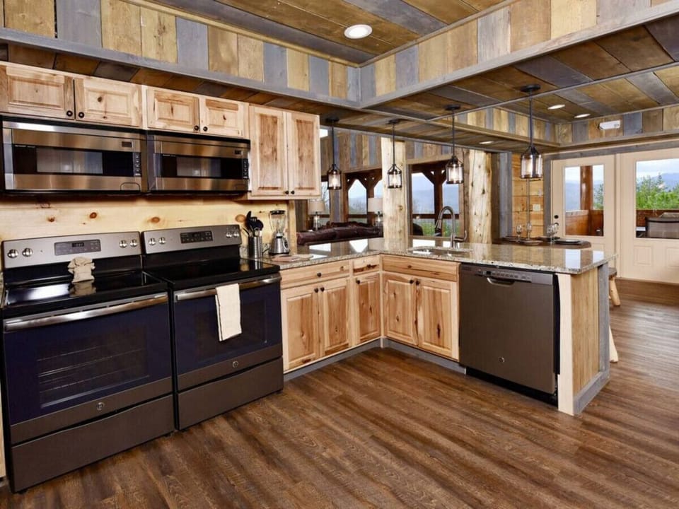 A kitchen peninsula overlooks indoor & outdoor dining areas, & the great room