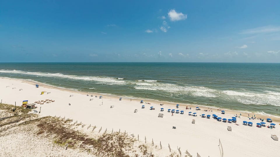 Gaze at the inviting shoreline with colorful umbrellas and gentle waves, perfect for a day of relaxation