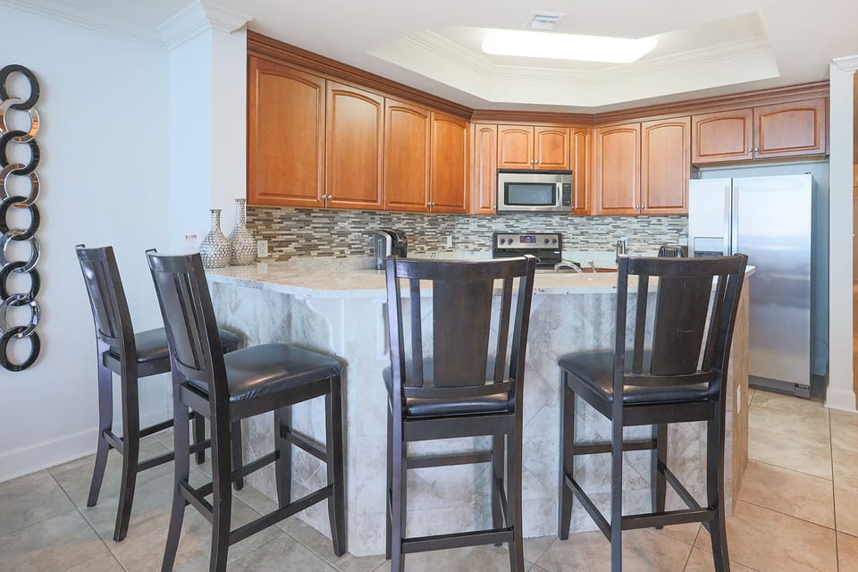 The kitchen features elegant wood cabinetry, a stainless steel refrigerator, and a convenient Keurig coffee maker