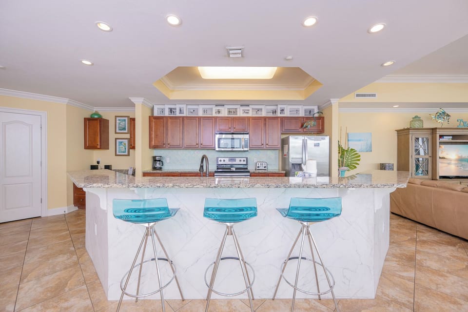 Modern kitchen with sleek granite countertops, stainless appliances, and stylish blue bar stools