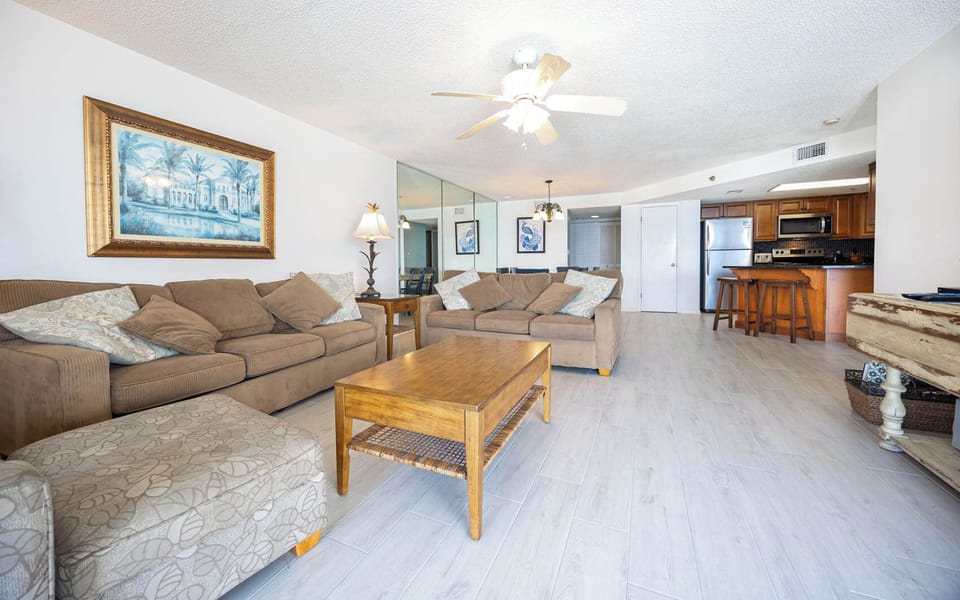 The inviting living area features two plush sofas, a queen sleeper, coffee table, and a view of the modern kitchen