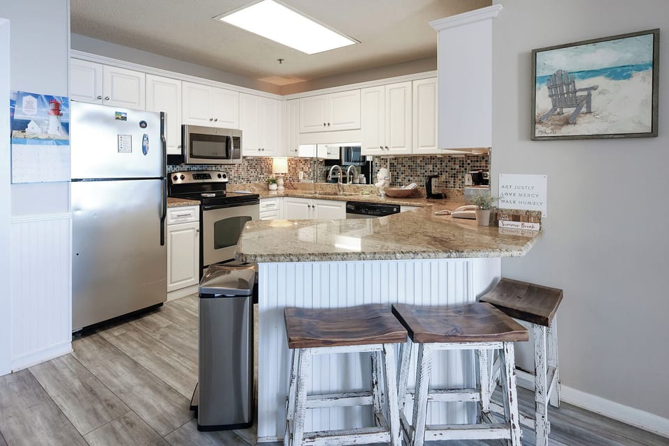 Bright kitchen featuring white cabinetry, a granite countertop, and a breakfast bar with rustic stools for casual dining