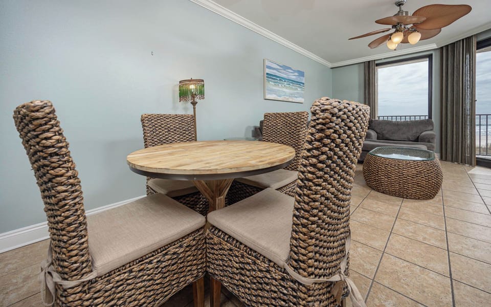 Gather around the round dining table with woven chairs, enjoying the inviting coastal decor and natural light