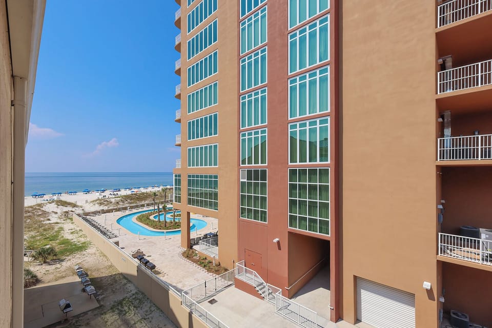 This view showcases a vibrant pool area surrounded by palm trees, with beach access just steps away