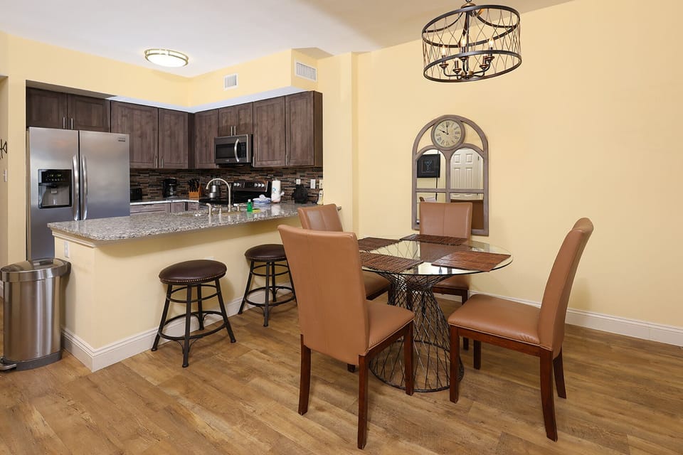 This modern kitchen features stainless appliances, granite countertops, and a cozy dining area with stylish seating