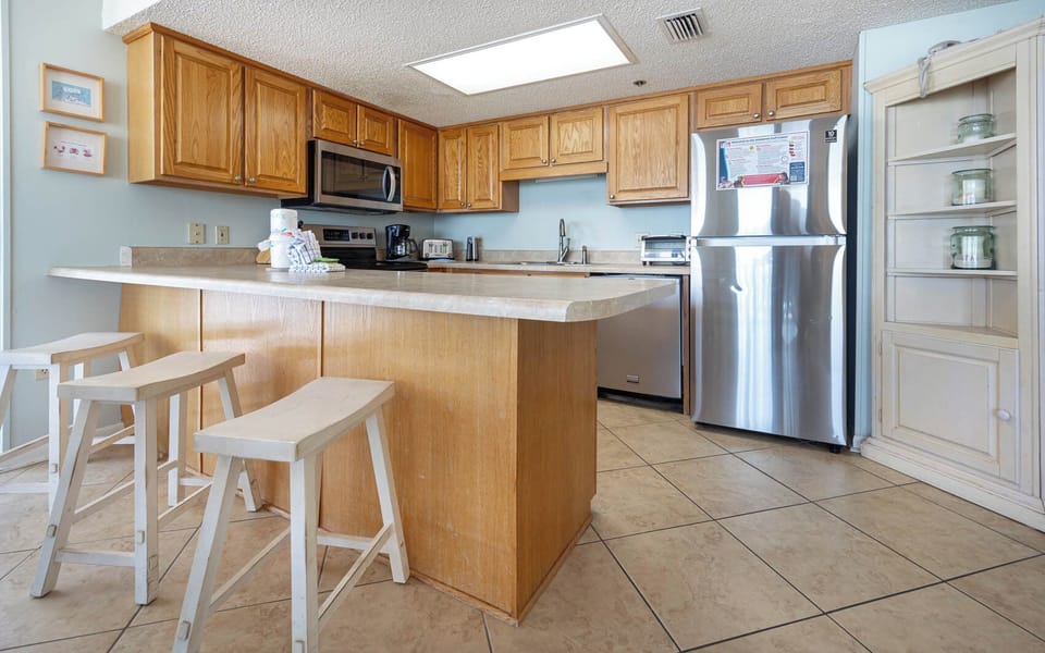 Prepare meals in the bright kitchen, featuring wood cabinets, stainless appliances, and a convenient breakfast bar